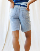 Person wearing light blue denim shorts on a plain background