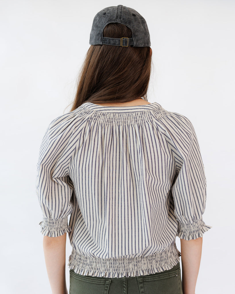 Person wearing a striped blouse and cap on a white background