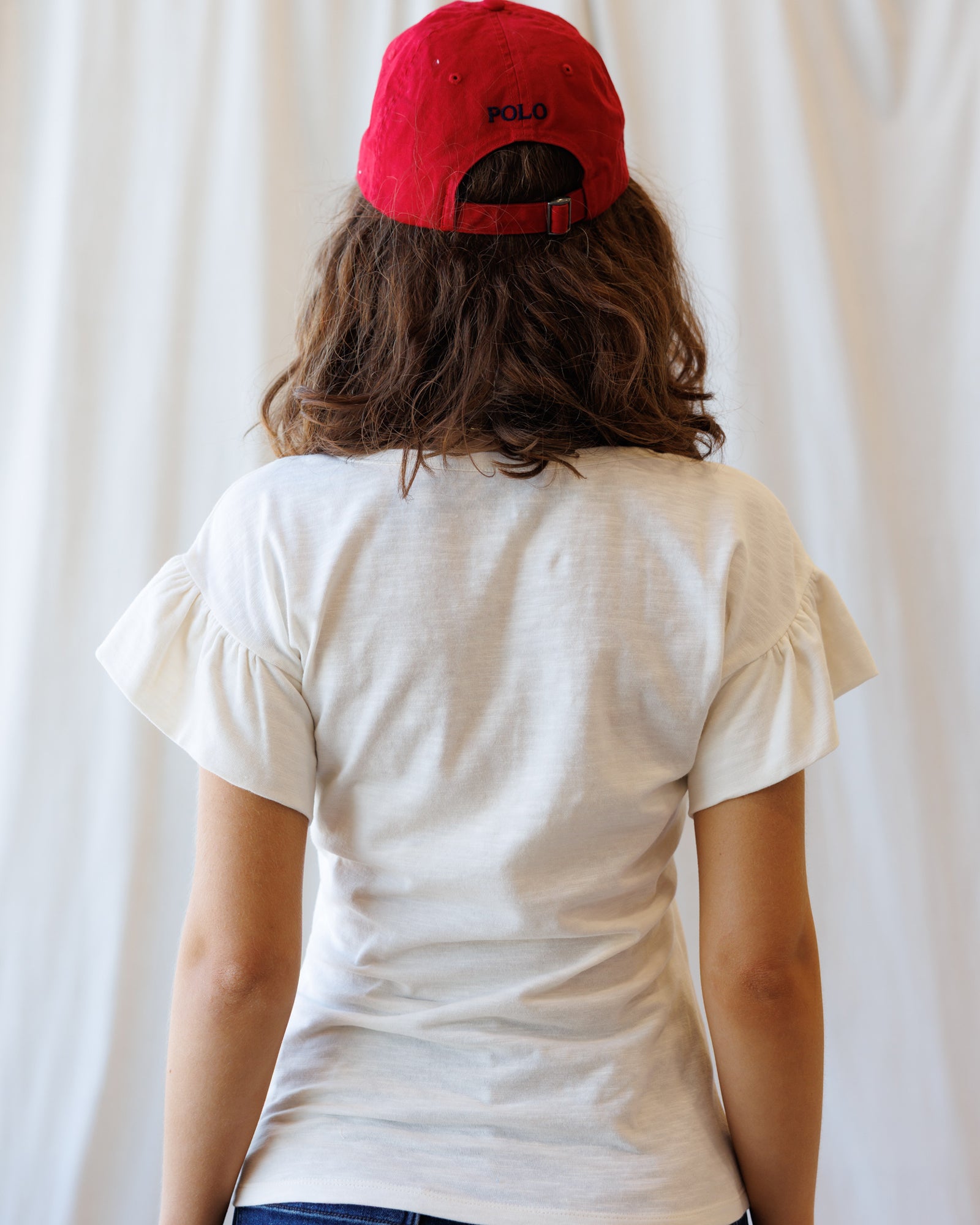 Person wearing a white t-shirt and red cap with 'Kodak' logo against a plain background