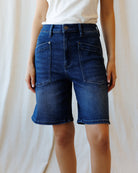 Person wearing blue denim shorts on a plain background