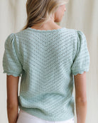 Light blue knitted top worn by a person against a neutral background