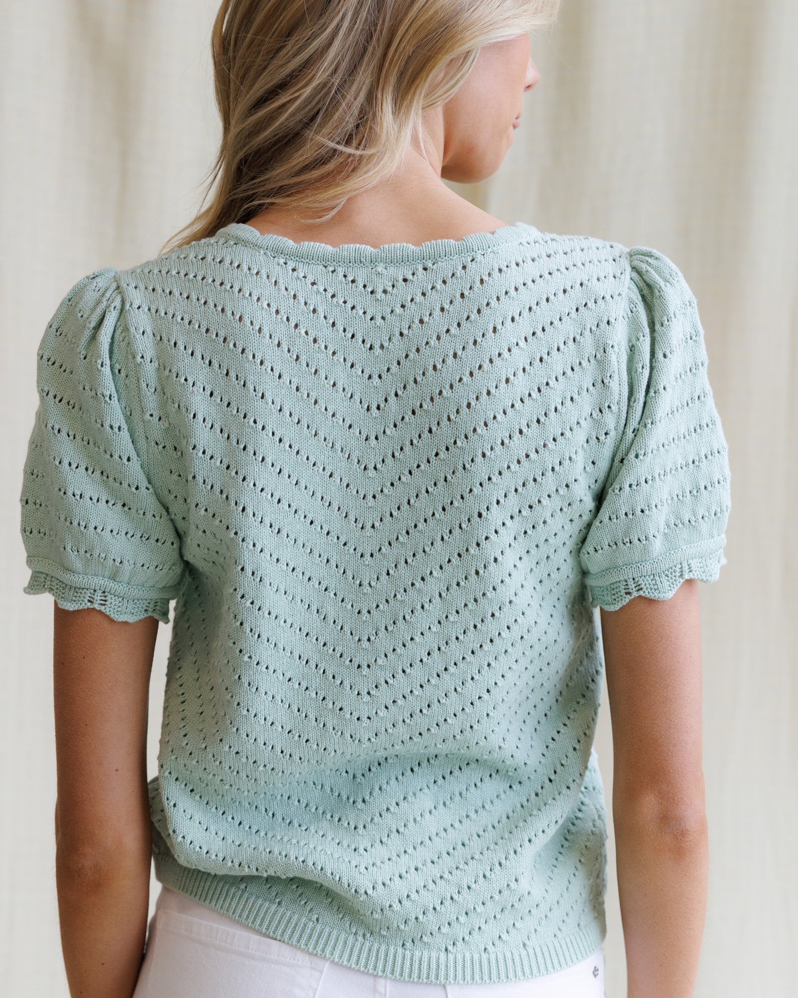 Light blue knitted top worn by a person against a neutral background