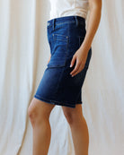 Person wearing a blue denim skirt against a plain background