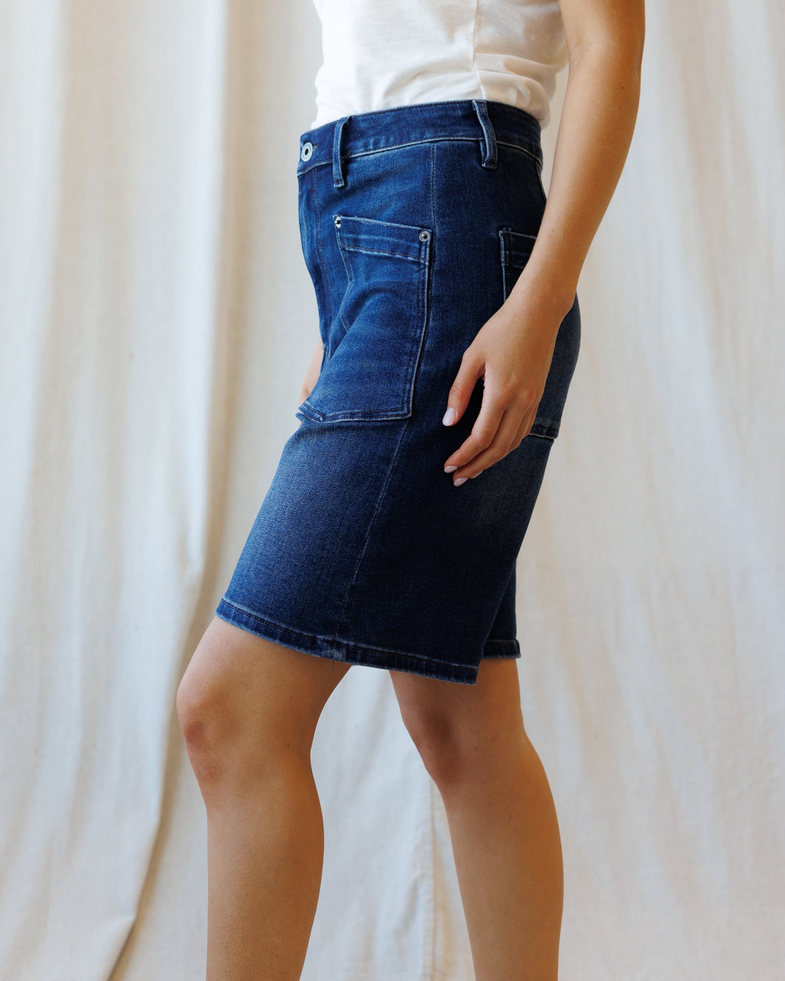 Person wearing a blue denim skirt against a plain background