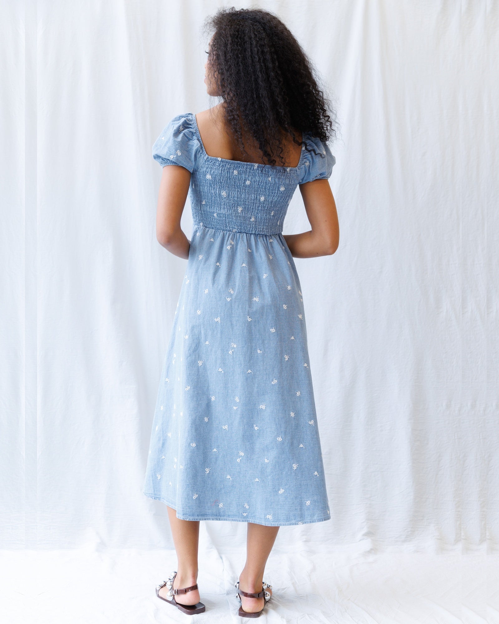 Woman wearing a light blue dress with star pattern against a white background