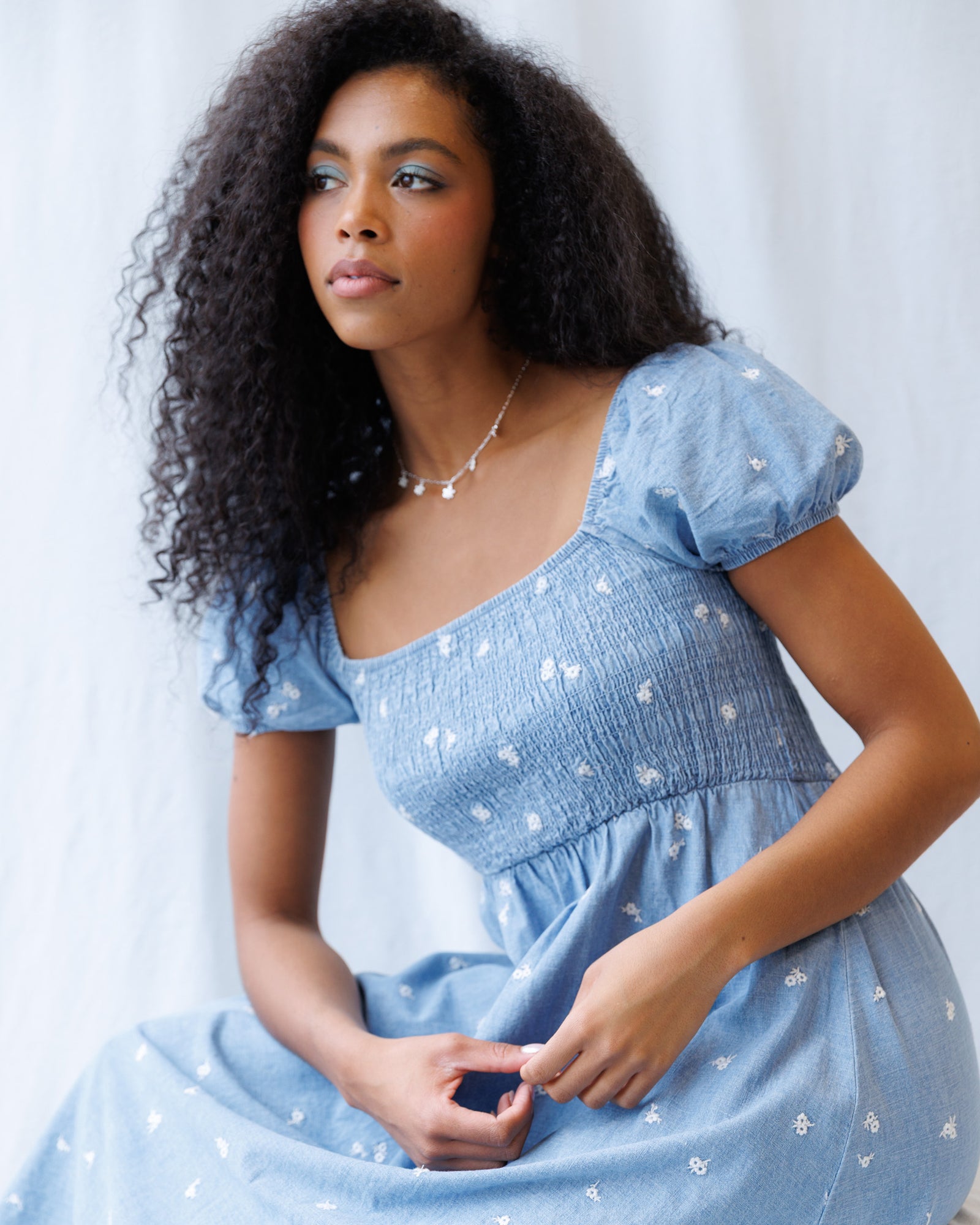 Woman wearing a blue dress with white patterns against a light background