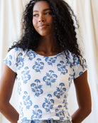 Woman wearing a white t-shirt with blue floral pattern against a plain background