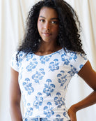 Woman wearing a white t-shirt with blue floral pattern against a plain background