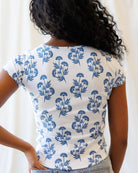 Person wearing a white t-shirt with blue floral pattern against a plain background