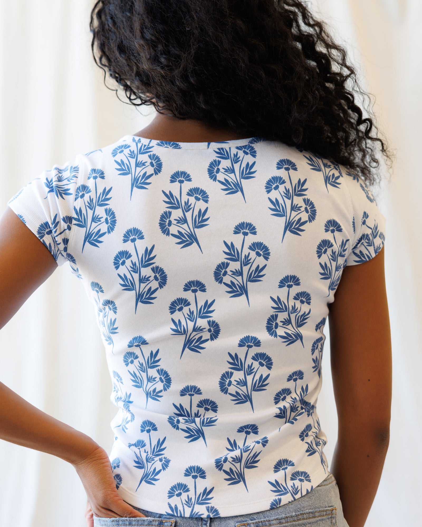 Person wearing a white t-shirt with blue floral pattern against a plain background
