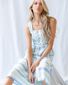 Woman wearing a light blue and white striped dress against a white background