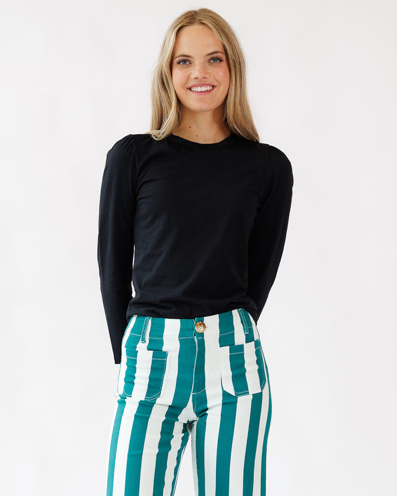 Woman wearing a black top and green and white striped pants on a white background