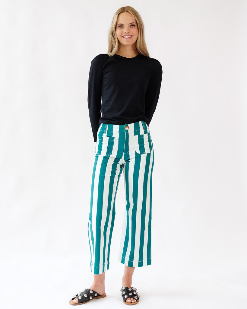Woman wearing a black top and green and white striped pants on a white background