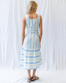 Woman wearing a striped dress against a white curtain background