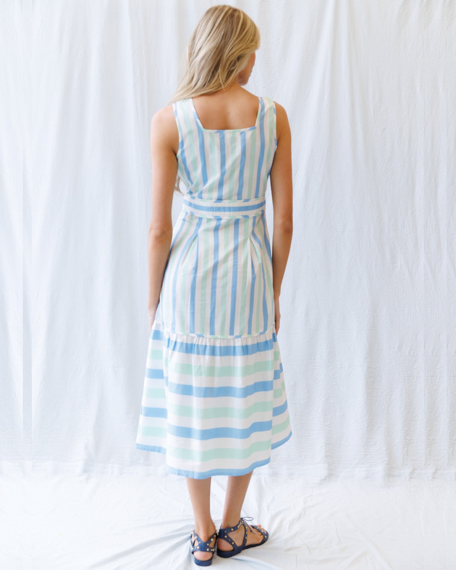 Woman wearing a striped dress against a white curtain background