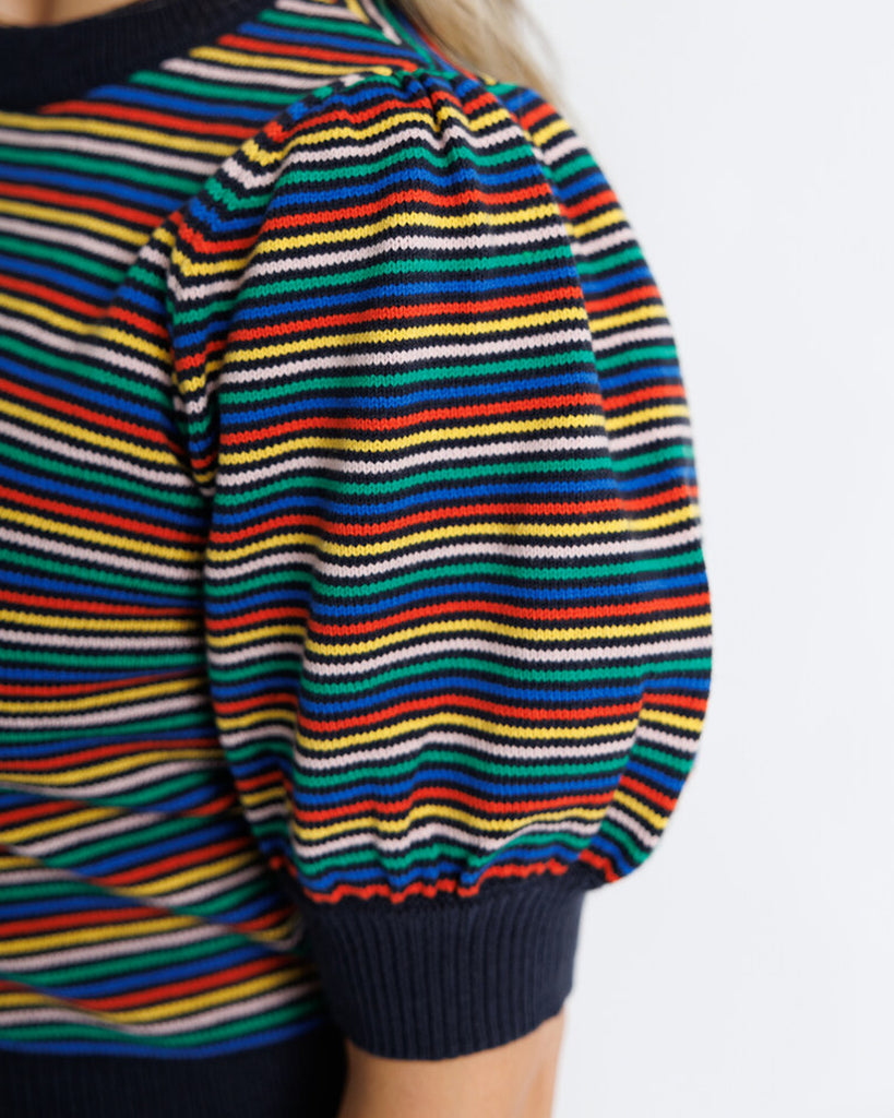 Model wearing a black with bright stripes short puffed sleeve crew neck pullover.