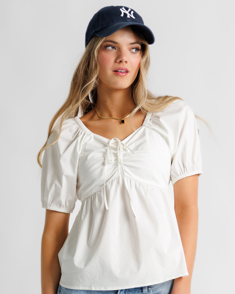 Model wearing a white short sleeve sweetheart neckline peplum blouse
