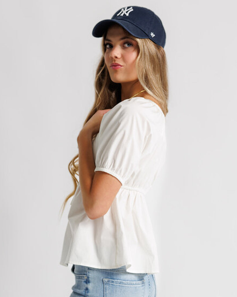 Model wearing a white short sleeve sweetheart neckline peplum blouse