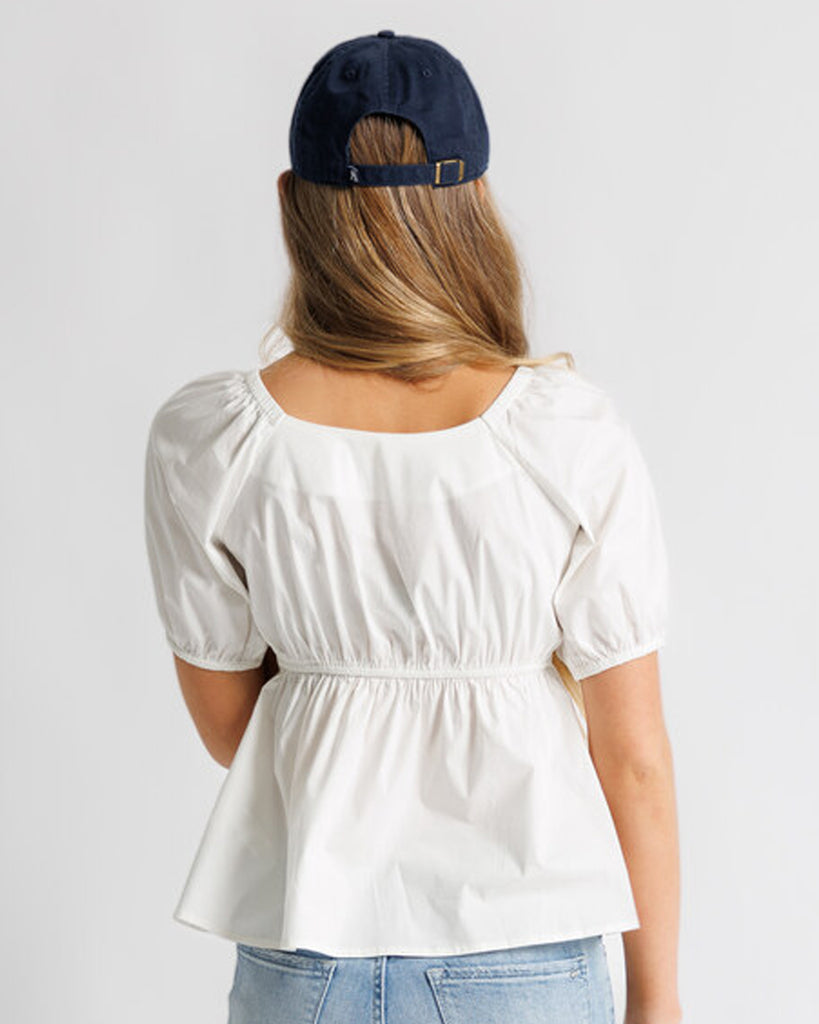 Model wearing a white short sleeve sweetheart neckline peplum blouse