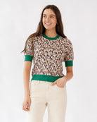 Woman wearing a leopard print top with green trim on a white background