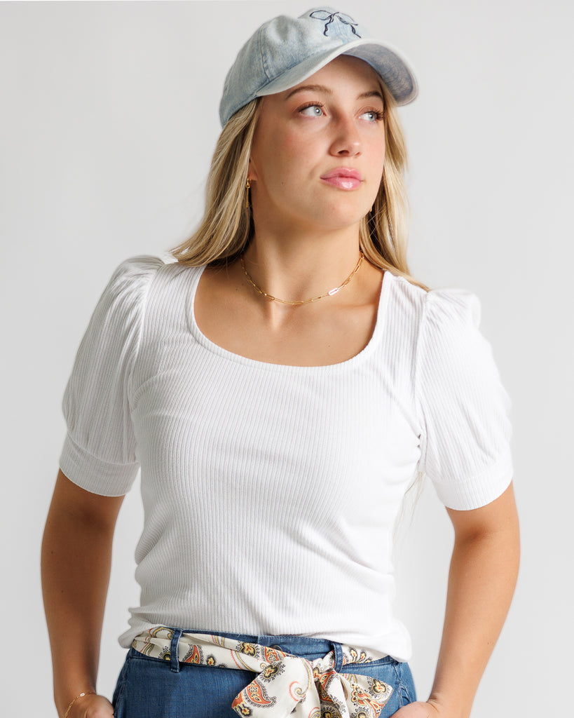 Model wearing a white short sleeve, scoop neck, ribbed tee