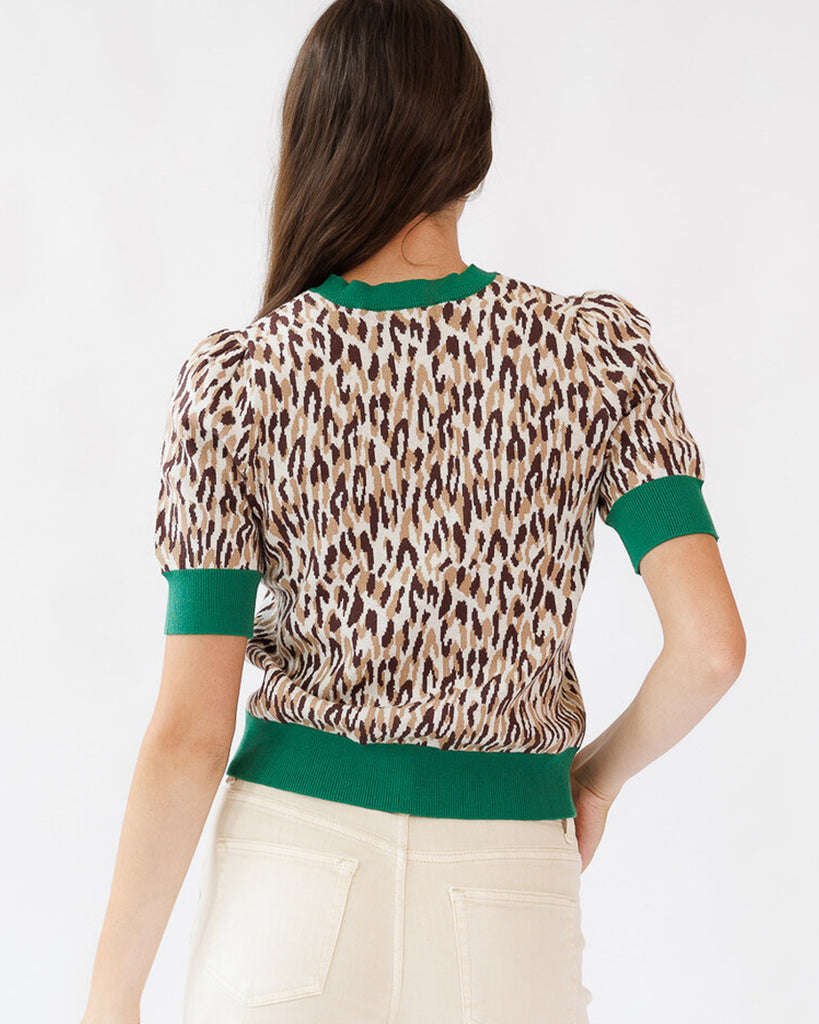 Woman wearing a leopard print top with green accents on a white background