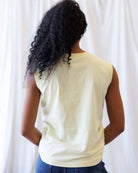 Person wearing a light-colored sleeveless top against a white background