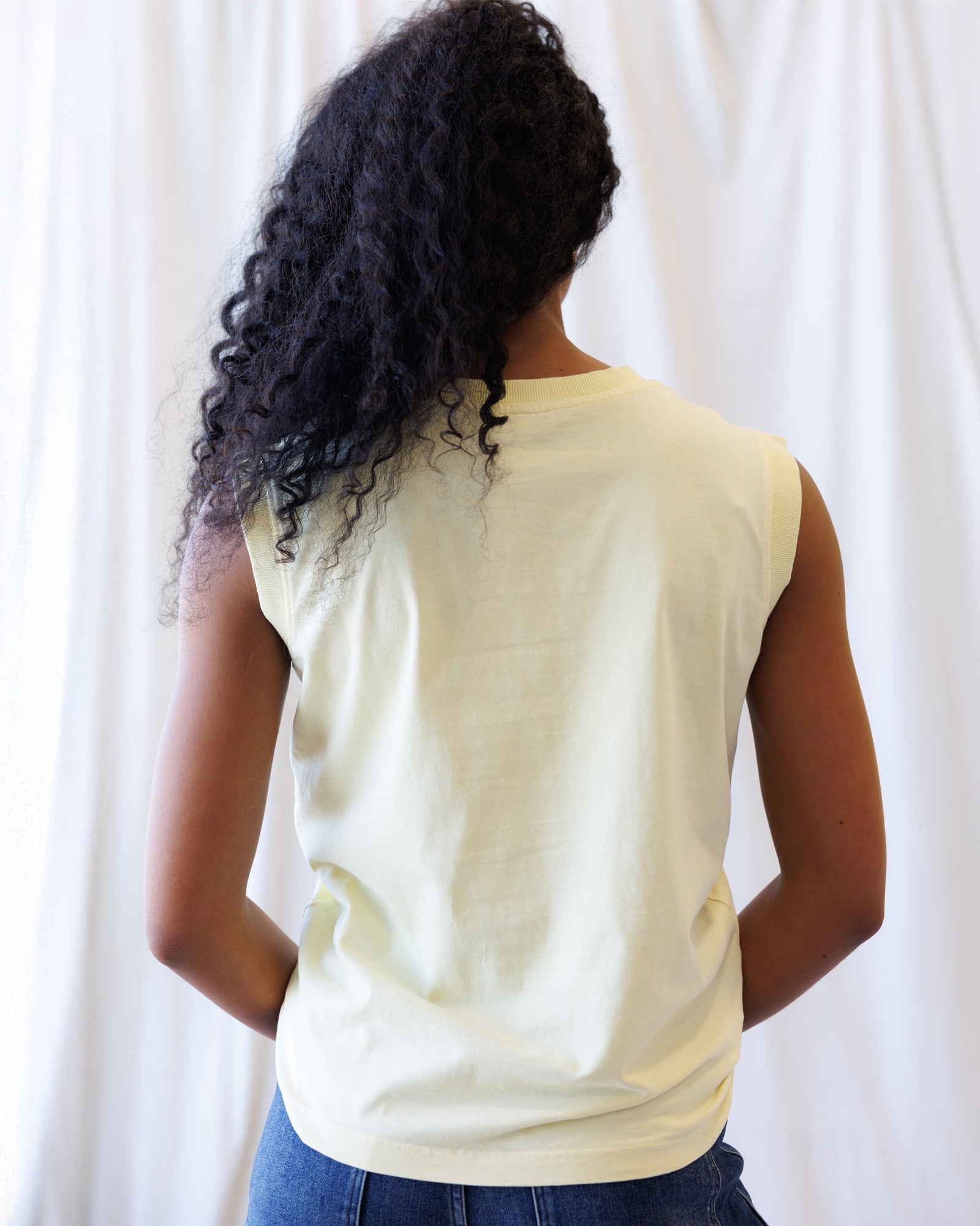 Person wearing a light-colored sleeveless top against a white background