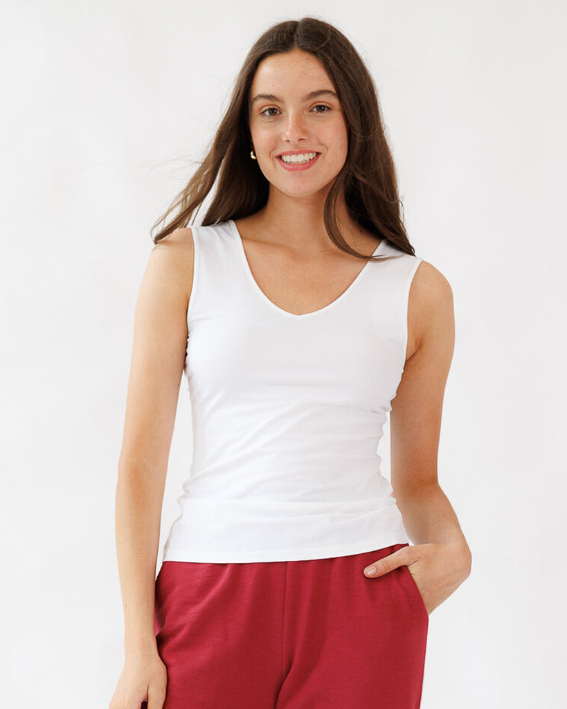 Woman wearing a white tank top and red pants on a white background