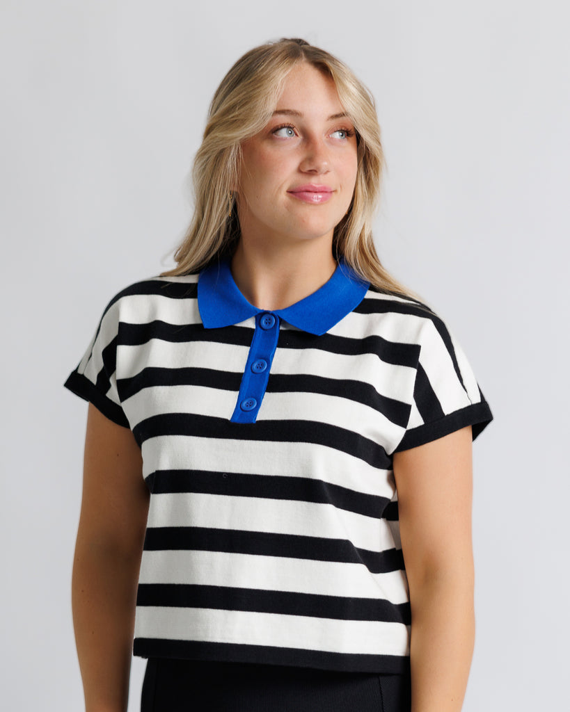 Model wearing a black and white striped short sleeve polo with a blue collar