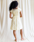 Person wearing a yellow dress standing in front of white curtains