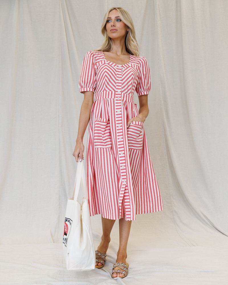 Image of a woman wearing a white and red striped midi dress with hands in front pockets