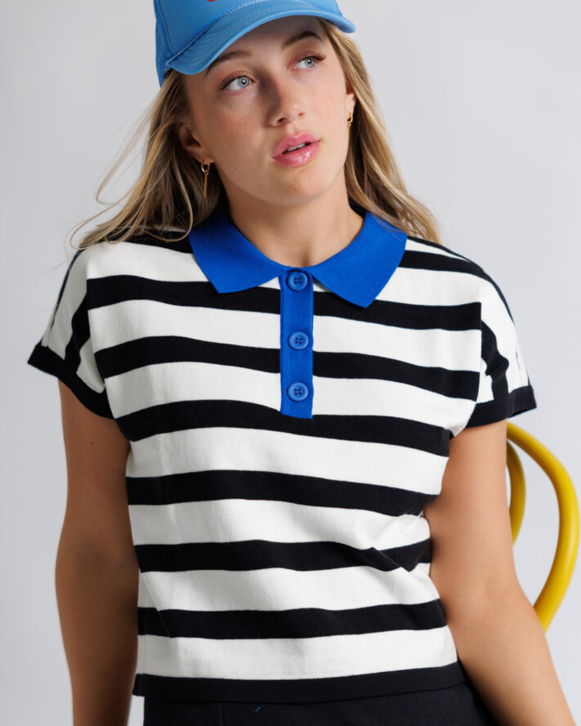 Model wearing a black and white striped short sleeve polo with a blue collar