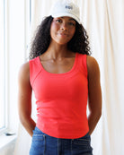 Woman wearing a red tank top and white cap with 'oui' logo indoors.