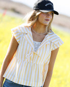 Woman wearing a yellow and white striped shirt with a blurred background