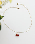 Gold necklace with red beads on a light background