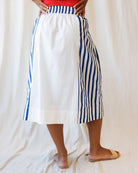 Person wearing a white skirt with blue stripes on a plain background
