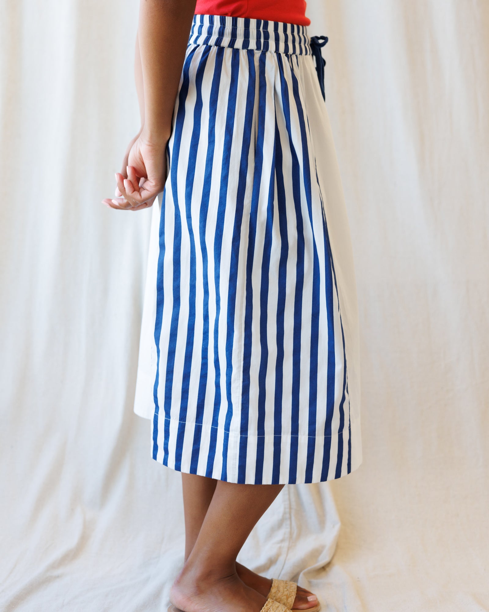 Person wearing a blue and white striped skirt against a plain background