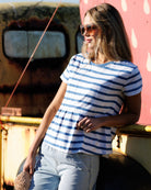 Woman wearing a blue and white striped shirt standing against a colorful wall.
