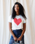 Woman wearing a white t-shirt with a red heart design against a plain background