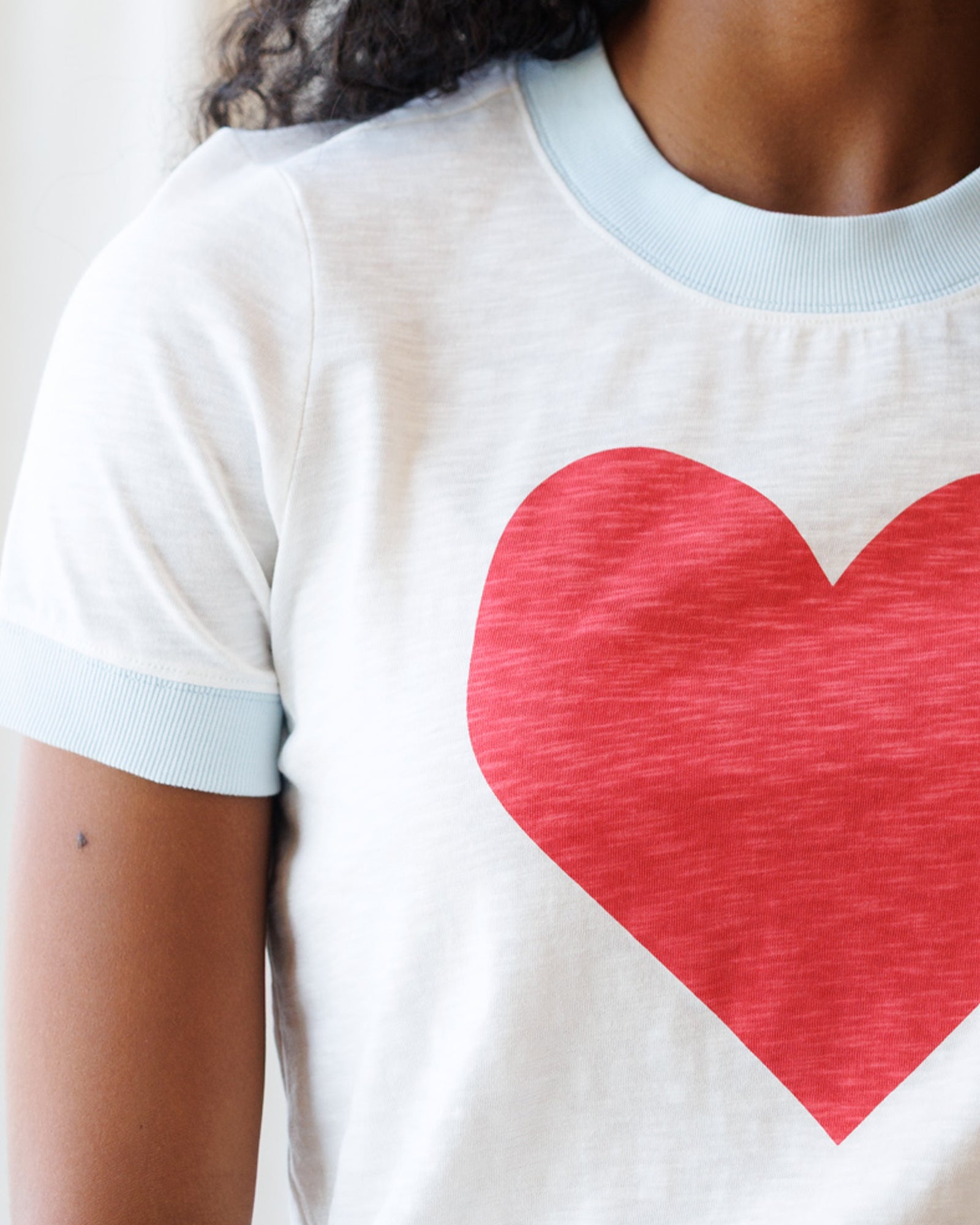 Person wearing a white t-shirt with a red heart design