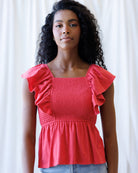 Woman wearing a red top with ruffled sleeves against a white background