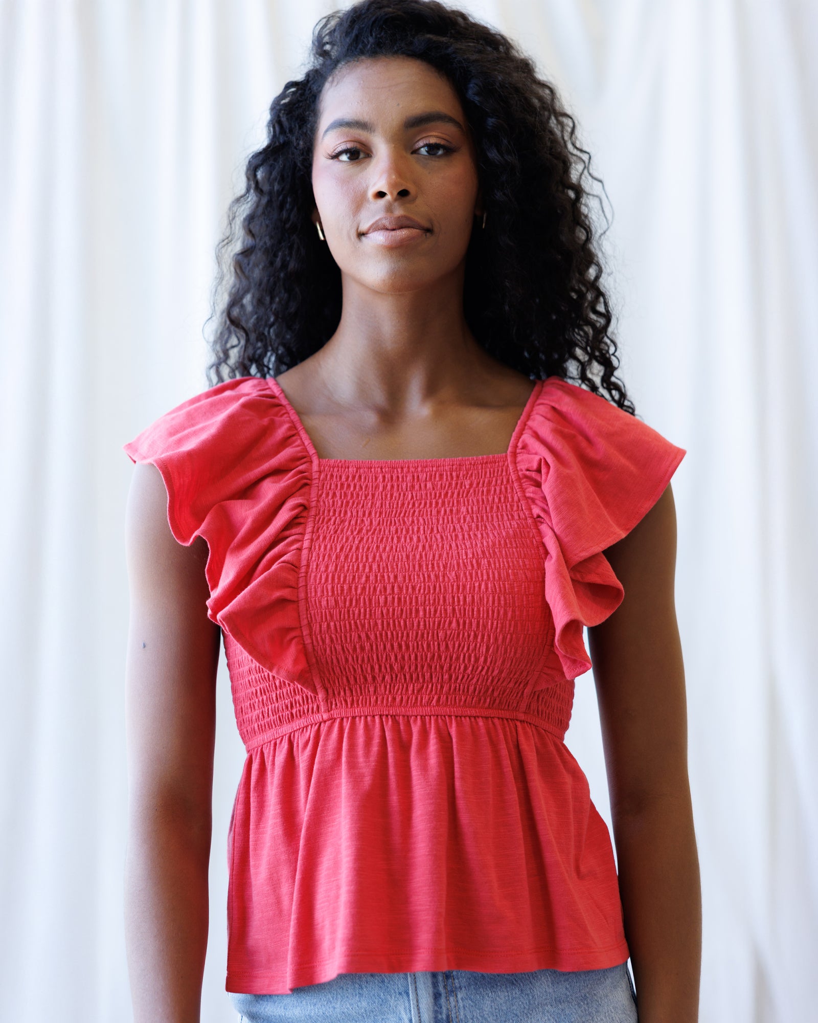 Woman wearing a red top with ruffled sleeves against a white background