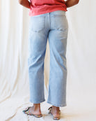 Person wearing light blue jeans and a pink top on a plain background