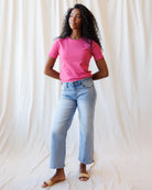 Person wearing a pink t-shirt and light blue jeans against a white background