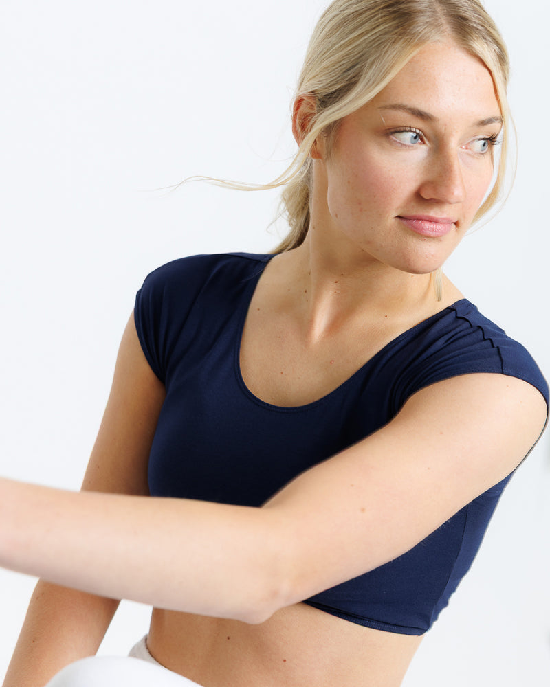 Model wearing a navy short sleeve scoop neck cropped tee.