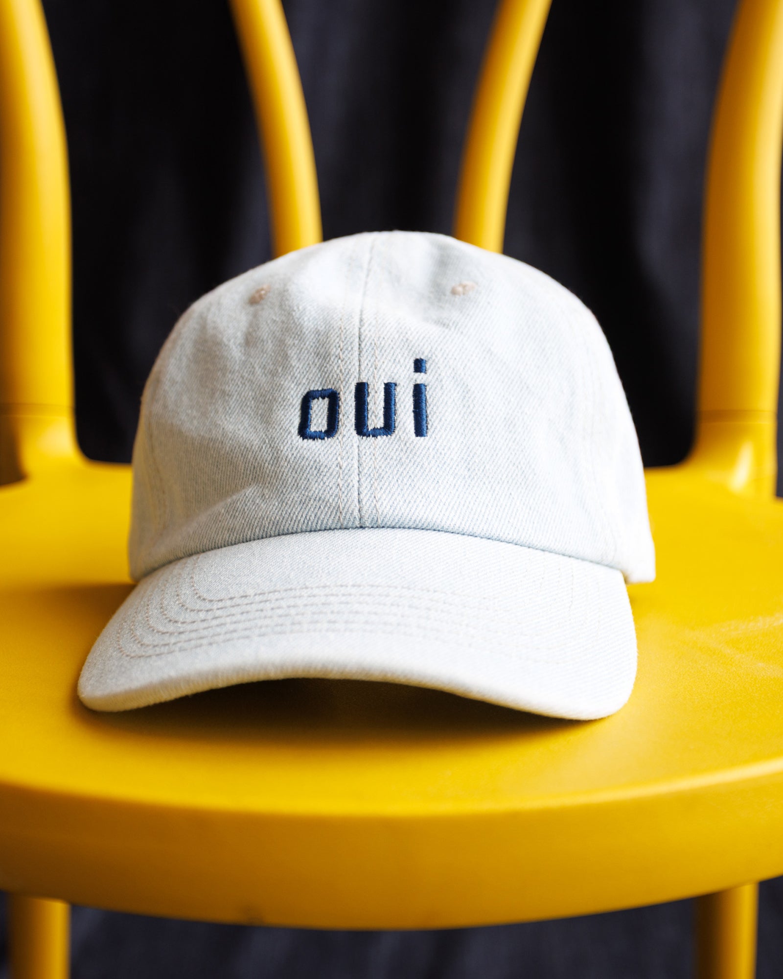 Image of a light wash denim hat with "OUI" embroidered in navy thread