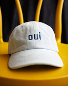 Image of a light wash denim hat with "OUI" embroidered in navy thread