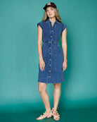 Woman wearing a denim dress against a teal background