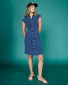 Woman wearing a blue denim dress against a teal background